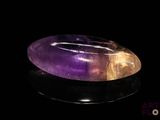 a close up of a purple and yellow quartz stone on a black surface