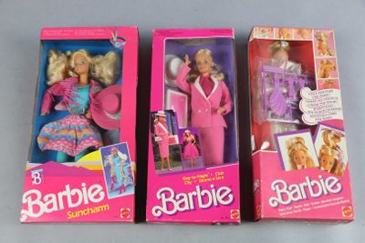 three barbie dolls are in their boxes on a gray surface