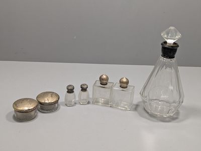 une petite bouteille en verre avec un bouchon argenté, à côté d'une autre petite bouteille en verre avec un bouchon argenté