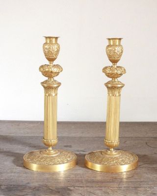 deux bougeoirs en or posés sur une table en bois