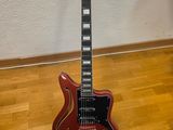 une guitare électrique rouge posée sur un parquet en bois massif
