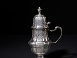 an antique silver coffee pot on a black background