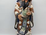 an oriental figurine of a man holding a bowl of flowers