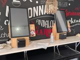 two computer monitors on a desk with a chalkboard wall behind them