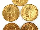 quatre types différents de pièces d'or sont présentés sur une surface blanche