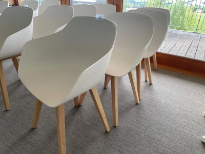 four white chairs sitting in front of a large window
