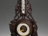 a wooden clock with a barometer on top of it