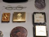 une table sur laquelle se trouvent de nombreux objets, notamment une horloge, un sac à main, des lunettes et une montre