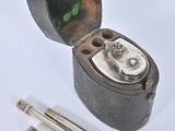 a small metal box with a pen and a pencil in it
