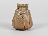an old bronze vase with a face on it sitting on a white surface