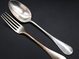 two silver spoons and a fork on a black background