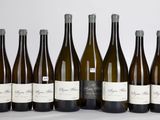 six bouteilles de vin sont alignées sur une surface blanche