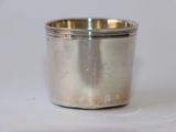 une tasse en argent posée sur une surface blanche
