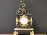 une statue de femme assise au sommet d'une horloge