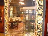 a gold framed mirror in the middle of a room