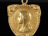 un pendentif en or orné d'une tête de femme au centre