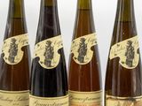 four bottles of wine are lined up on a white surface