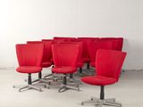 six chaises de bureau rouges dans une pièce aux murs blancs