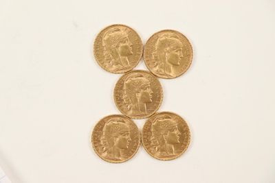 four gold coins sitting on top of each other on a white surface