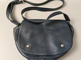 the small black purse is sitting on a white table