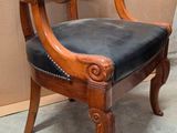 a wooden chair with a black leather seat in a room
