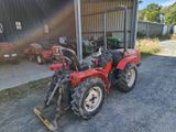 un tracteur rouge garé devant un bâtiment