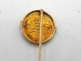 a gold brooch with a gold coin on it