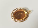 a close up of a gold plated pendant on a white surface