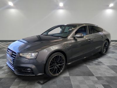 une berline Audi grise garée dans un garage au sol carrelé