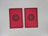 two red cards with black designs on them sitting on a white surface