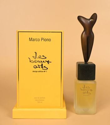 a close up of a bottle of perfume next to a statue