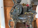 a man standing next to a statue of a man on a horse