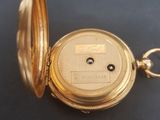 an image of a gold pocket watch sitting on a black surface