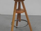 wooden stool with metal legs and a wooden seat on a concrete floor