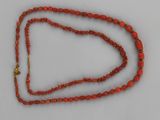 a close up of a red beaded necklace with a gold clasp