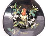 a black plate with a bird and flowers on it