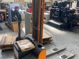 un chariot élévateur dans un entrepôt, chargé de nombreuses caisses