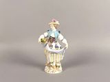 a small figurine of a woman with a basket of flowers