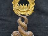 statue en laiton représentant un serpent tenant un coquillage doré, sur fond noir