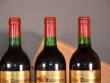 three bottles of red wine are lined up on a shelf