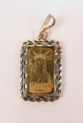 un pendentif en forme de pièce d'or sur lequel est représentée la Statue de la Liberté