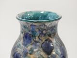 a blue and green vase sitting on a white surface