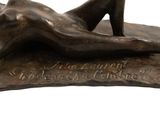 bronze sculpture of a woman laying on her stomach on a rock