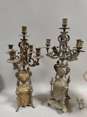 Plusieurs chandeliers anciens en argent sont posés sur une surface blanche