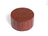 une petite boîte rouge avec un couvercle, posée sur une surface blanche