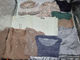 une valise remplie de vêtements et des vêtements posés par terre
