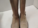 une paire de bottes beiges posée sur une table blanche