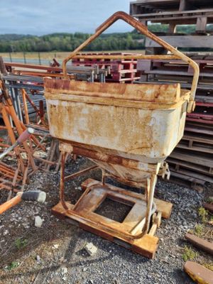 une machine rouillée posée par terre à côté d'un tas de ferraille