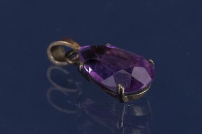 un gros plan d'un pendentif en pierre précieuse violette posé sur une surface bleue