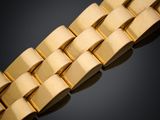 gros plan d'un bracelet en or sur une surface noire